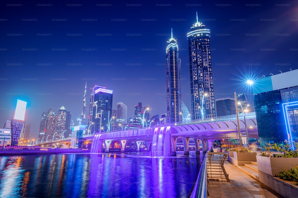高い高層ビルに何千もの小さなライトが灯る夜のドバイのダウンタウンにあるライトアップされた滝の橋。UAEの人気観光スポット
