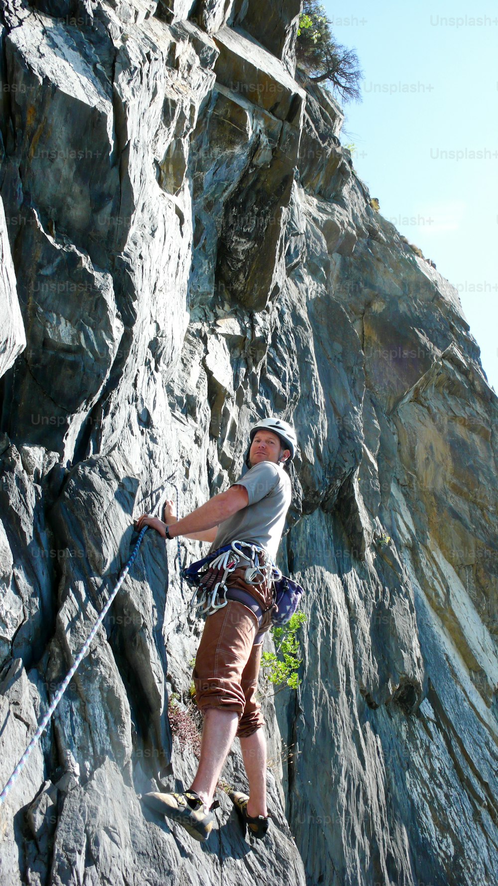 スイスのアルプスのスラブ石灰岩登山ルートを山岳ガイドのロッククライマーが晴れた日に