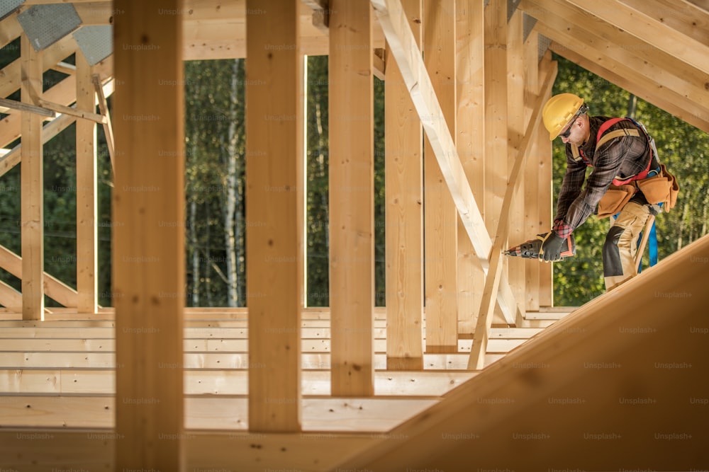 Lavoro di telaio a scheletro in legno. Operaio edile professionista con pistola sparachiodi. Tema industriale.