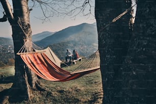 Young couple having breakfast while sitting by the campfire in mountains