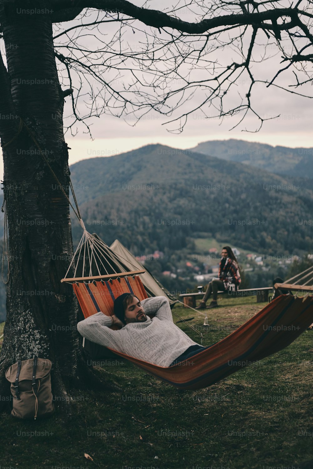 Handsome young man lying in hammock while camping with his girlfriend