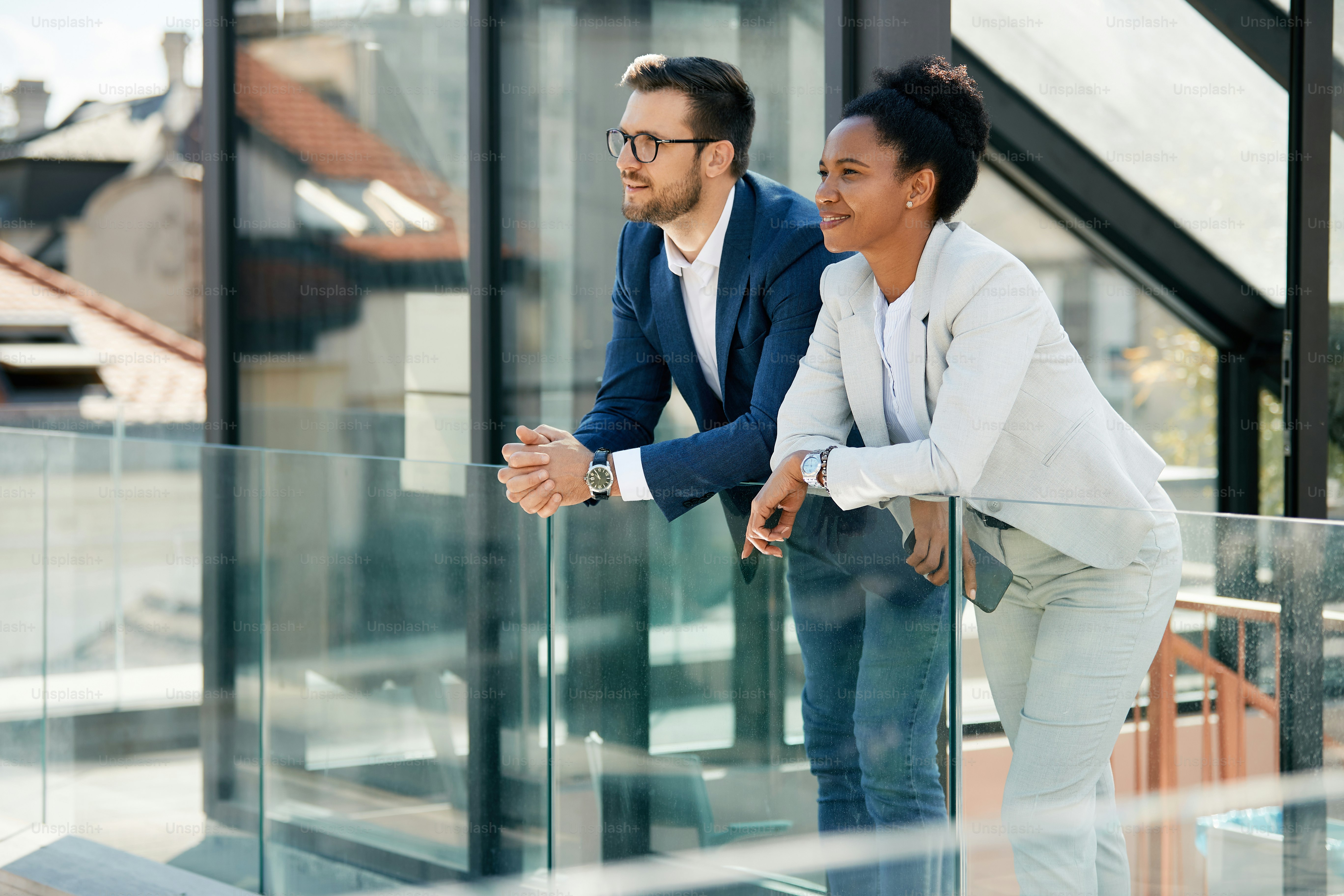 Feliz empresária afro-americana e seu colega desfrutando durante uma pausa na varanda de um prédio de escritórios.