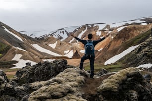 Traveler hiking at Landmannalaugar surreal nature landscape in highland of Iceland, Nordic, Europe. Beautiful colorful snow mountain terrain famous for summer trekking adventure and outdoor walking.