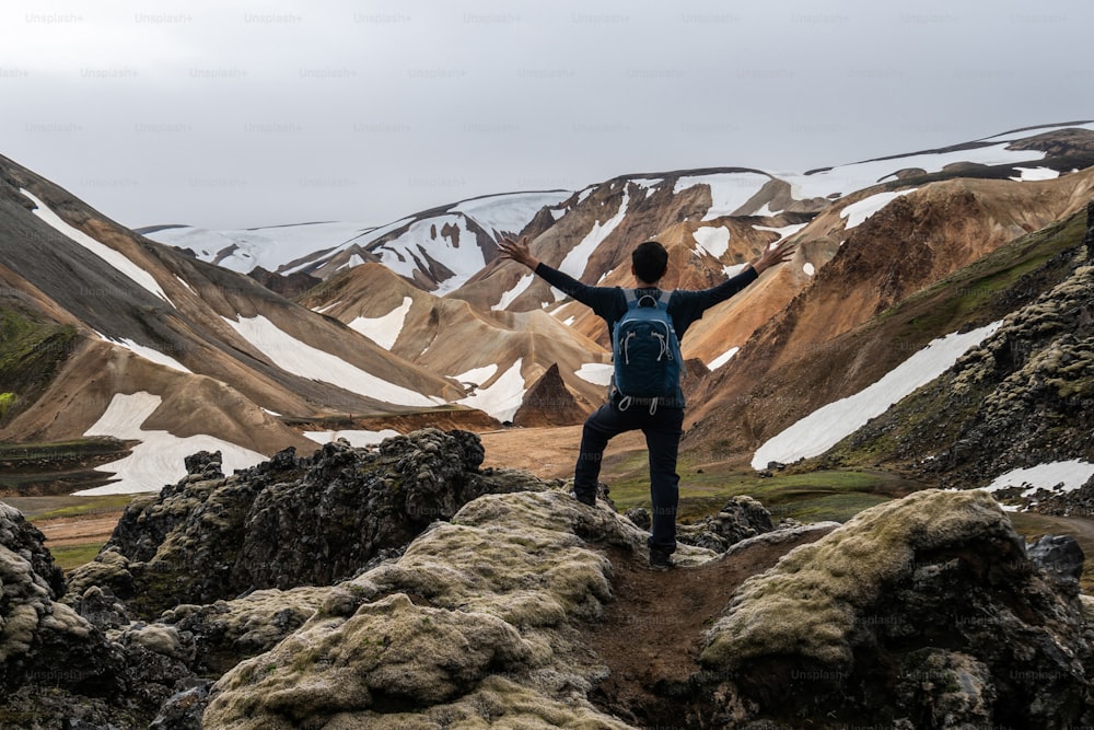아이슬란드, 북유럽, 유럽의 고원에 있는 란드만날뢰이가르(Landmannalaugar)의 초현실적인 자연 풍경에서 하이킹을 즐기는 여행자. 여름 트레킹 모험과 야외 산책으로 유명한 아름다운 다채로운 눈 산 지형.