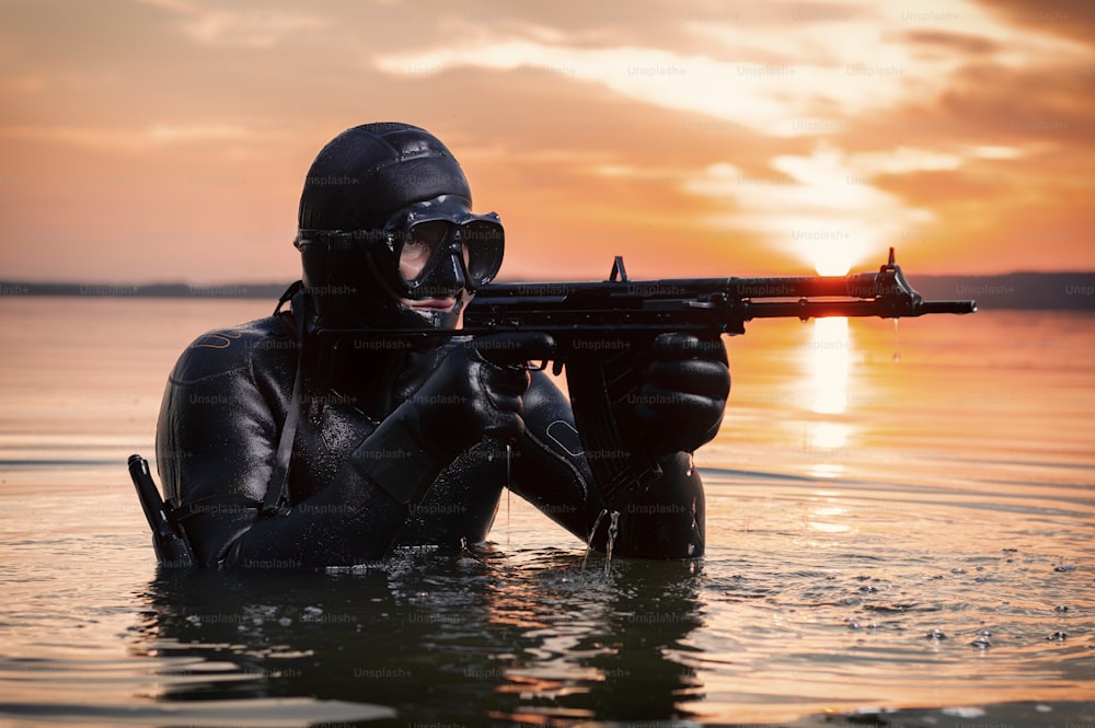 海兵隊員は水から上がり、武器を手にターゲットに向かって移動します。ビデオゲームの概念、広告、世界の不安定さ、国の紛争。ミクストメディア