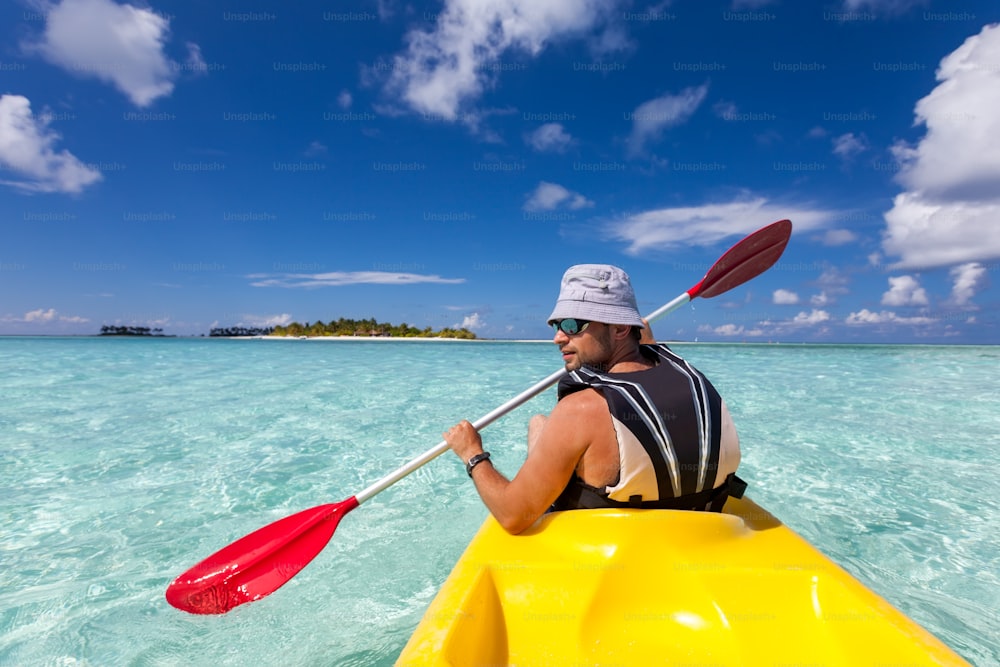 Young caucasian man kayaking in sea at Maldives