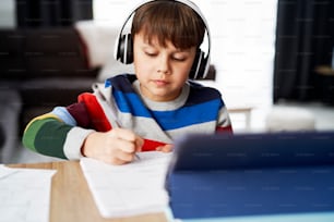 Schoolboy in headphone during homeschooling