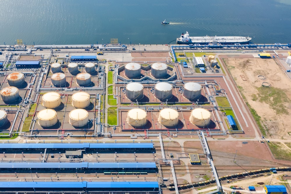 Aerial view of oil tankers moored at an oil storage silo terminal port and railway road infrastructure ground
