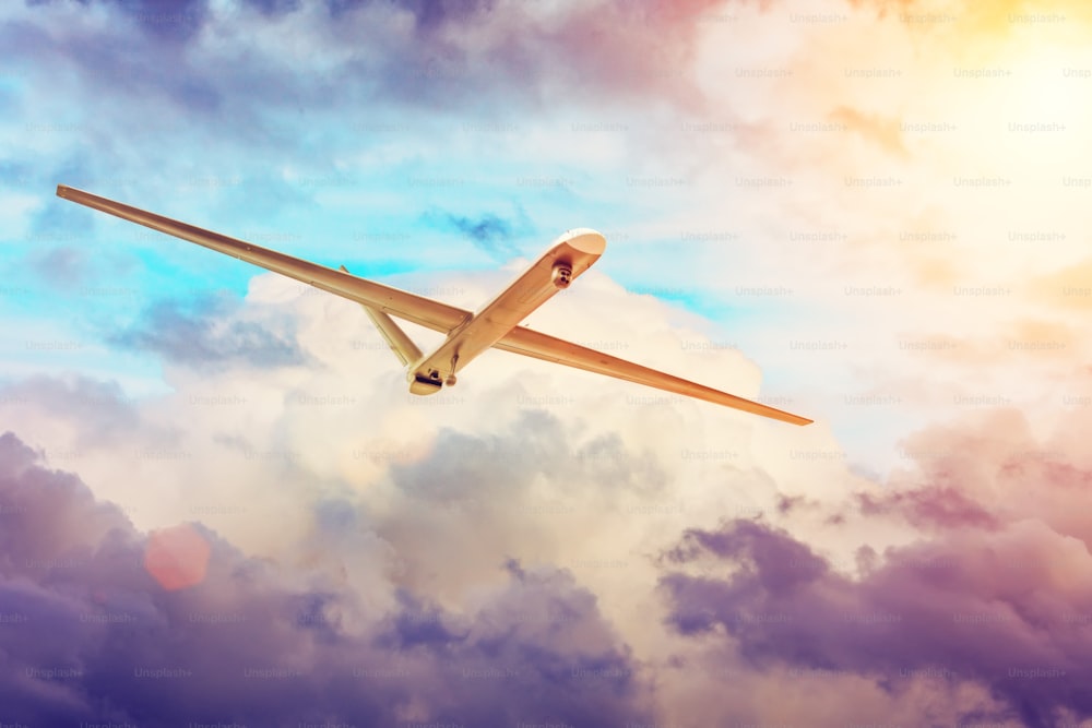 Un drone d’avion militaire sans pilote vole dans le ciel nuageux au coucher du soleil