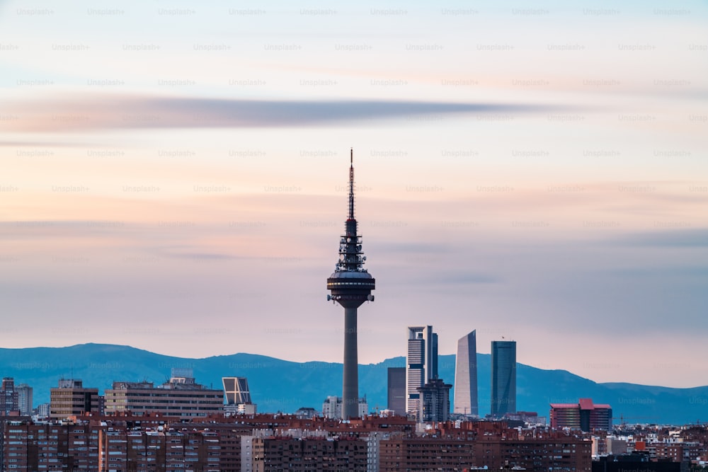 La ligne d’horizon de Madrid au crépuscule vue depuis le Cerro del Tio Pio, avec la tour de télévision et les gratte-ciel le long de Castellana à reconnaître. Exposition longue.