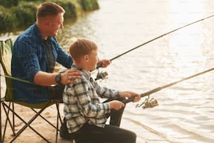Resting and having fun. Father and son on fishing together outdoors at summertime.