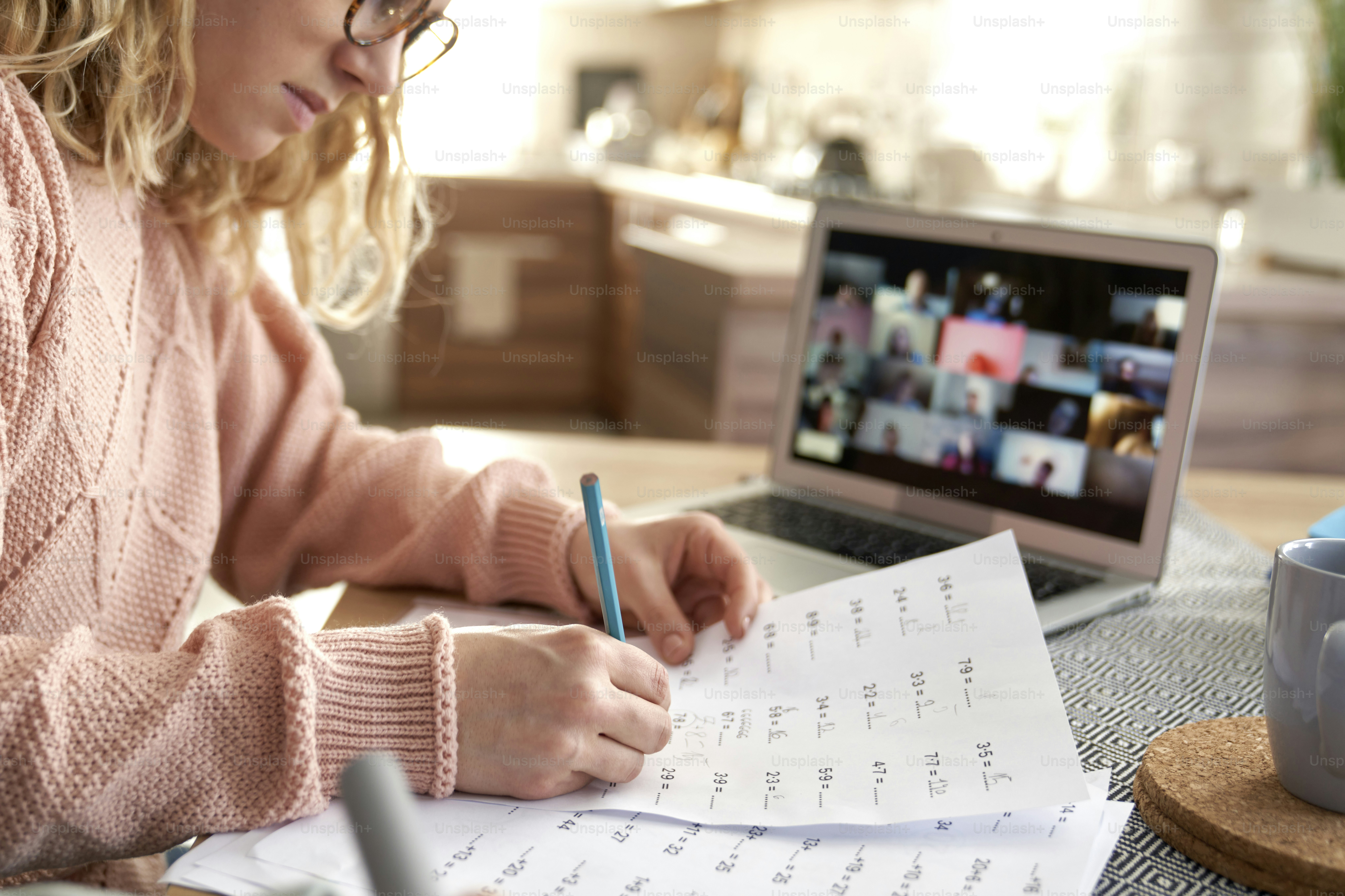 Young female teacher marks exam papers during online classes