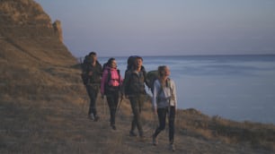 The four people with backpacks walking along the rocky coastline