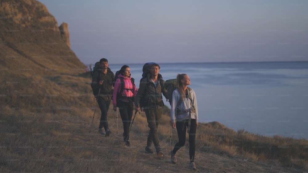 Die vier Personen mit Rucksäcken wandern entlang der felsigen Küste