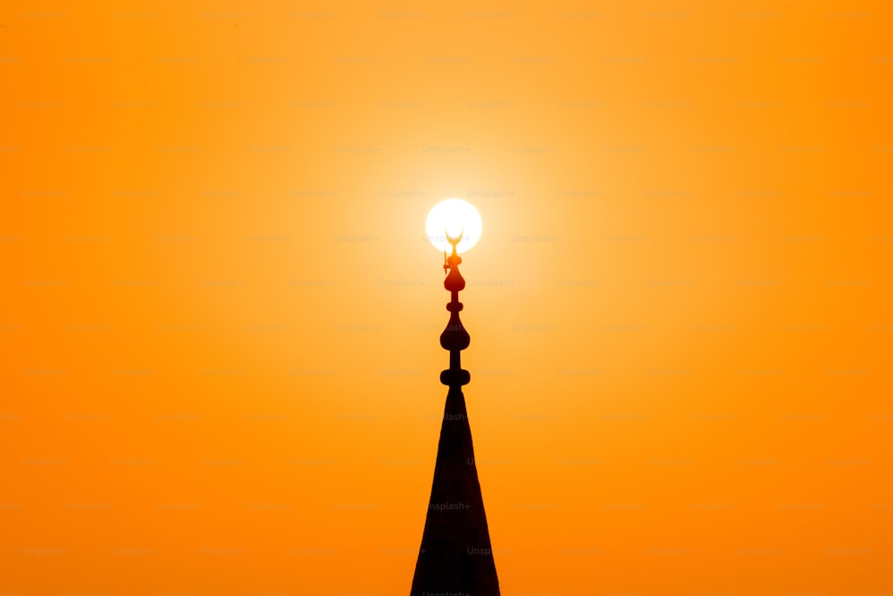 太陽とモスクのミナレットのシルエットと赤い夕日