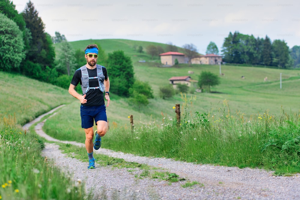 Young athlete with beard runs in rural hill landscape