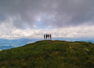Le quattro persone in piedi su una montagna contro il pittoresco paesaggio nuvoloso