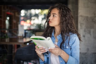 Learn for your better tomorrow.  African American girl at cafe reading book.