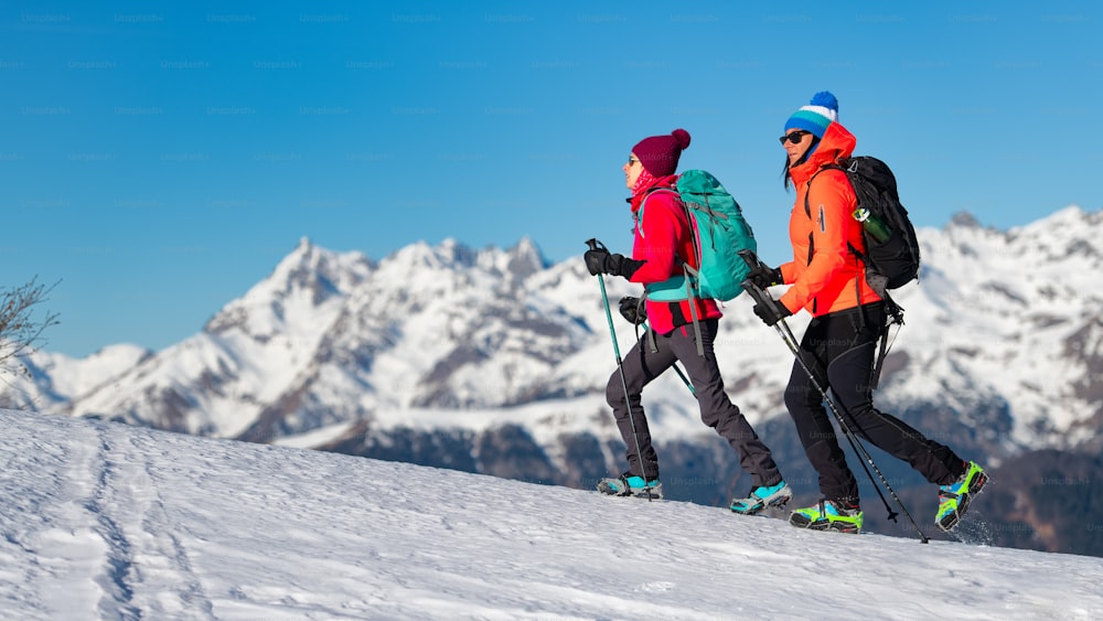 Mädchen wandern mit Steigeisen auf dem Schnee in den Bergen