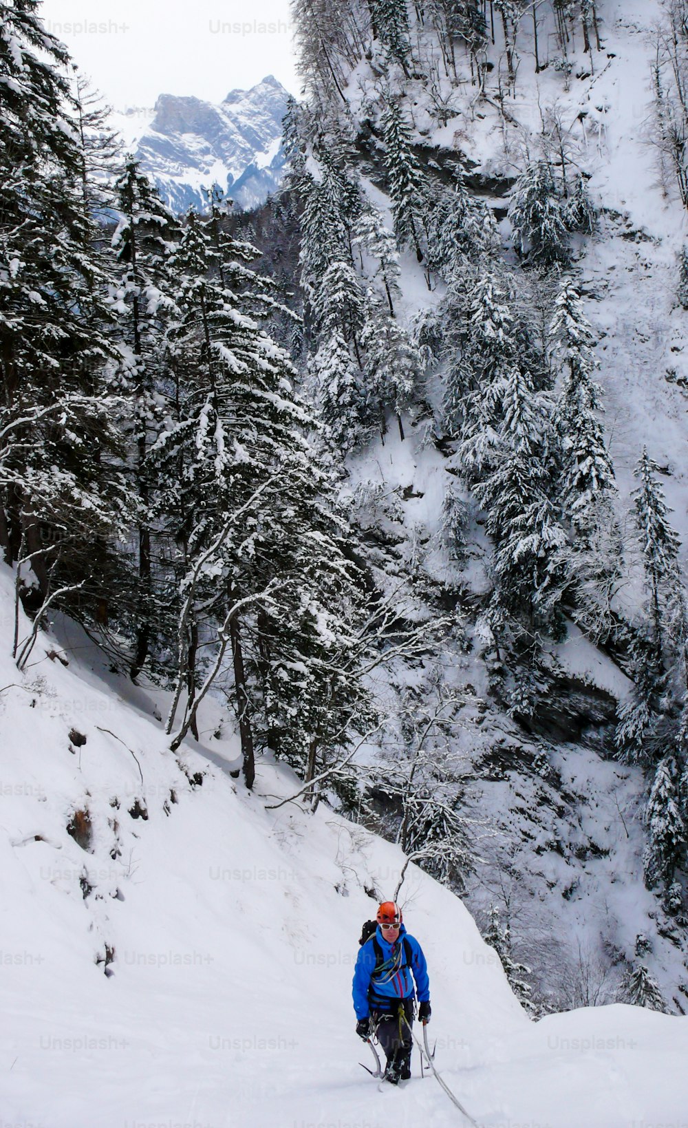 スイスのバート・ラガッツ近郊のタミナ渓谷で深い雪に覆われた凍った氷の滝のアイスクライマー