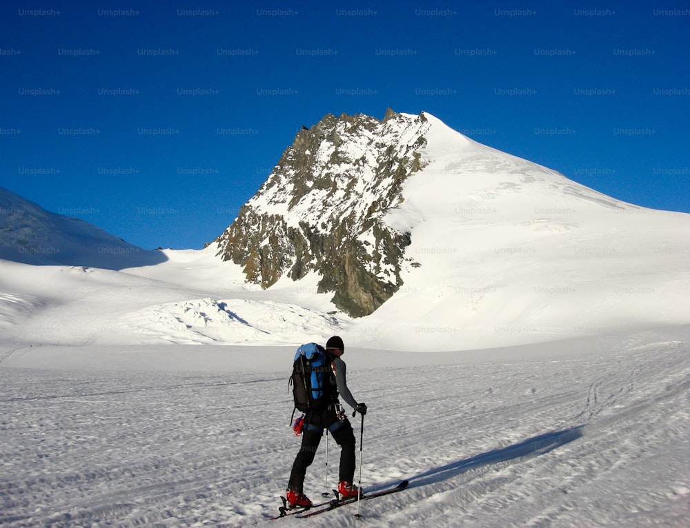 Uno sciatore fuoripista sulla strada per la vetta Rimpfischhorn nelle Alpi svizzere vicino a Zermatt