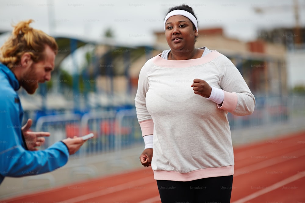 Trainer counting last seconds while young running woman getting closer to finish line