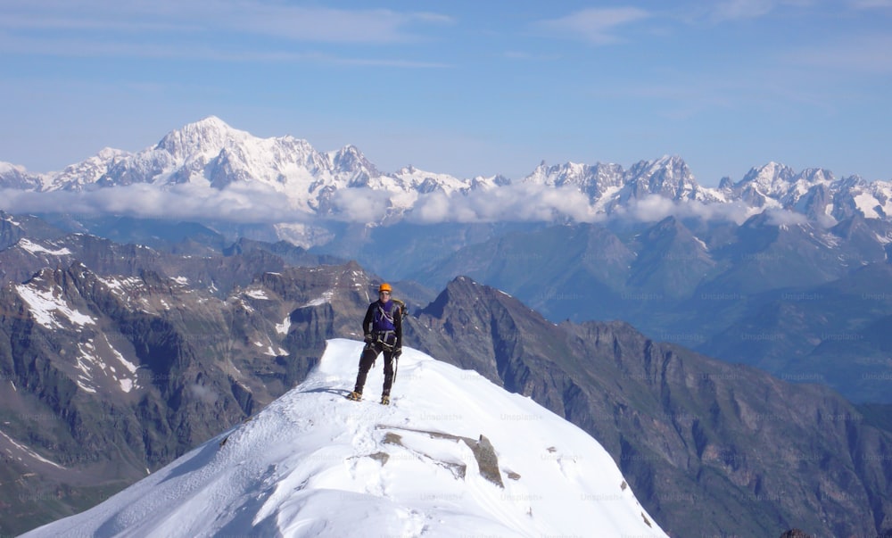 A male mountain climber on the summit of Gran Paradiso with a great view of Mont Blanc behind him