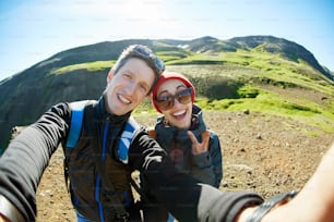 couple randonneurs voyageurs lors d’une promenade dans la vallée de la rivière Hveragerdi Islande. Randonnée dans les sources chaudes de Reykjadalur. femme et homme faisant un selfie en Islande