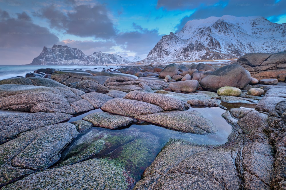 冬のノルウェー海のフィヨルドのビーチの岩夕日。ウタクリエフビーチ、ロフォーテン諸島、ノルウェー