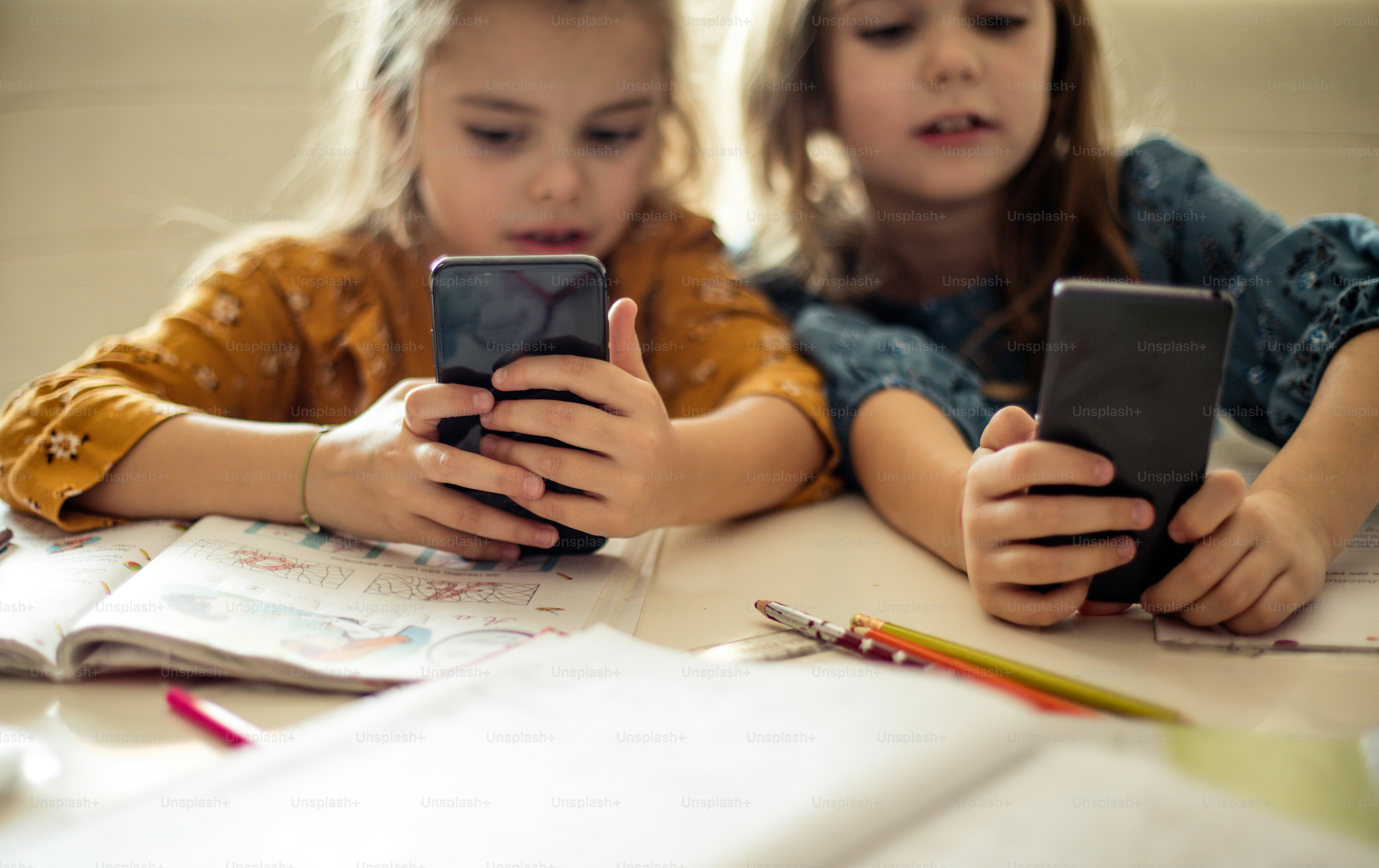 À quel jeu jouez-vous ? Deux petites écolières utilisant un téléphone intelligent.