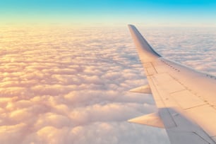 Travel by airplane concept. Wing of plane with scenic cloudy sky background