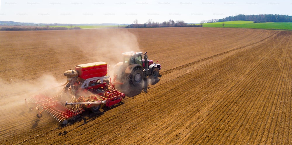 畑で作業する播種機を備えたトラクターの空中写真。上からの農業。