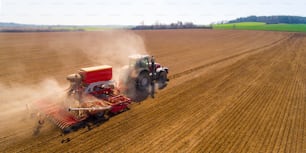 Vue aérienne d’un tracteur avec semoir travaillant dans un champ. L’agriculture vue d’en haut.