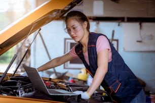 Una mujer mecánica de automóviles que repara automóviles con vista de capó abierto y verifica el nivel de aceite de motor para rellenar o limpiar en el servicio de garaje de automóviles