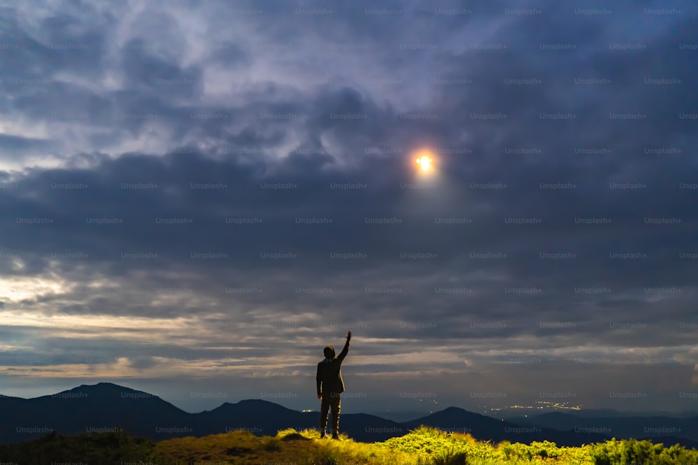 The UFO shines on a man standing on the mountain