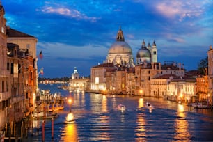 View of Venice Grand Canal with boats and Santa Maria della Salute church in the evening from Ponte dell'Accademia bridge. Venice, Italy