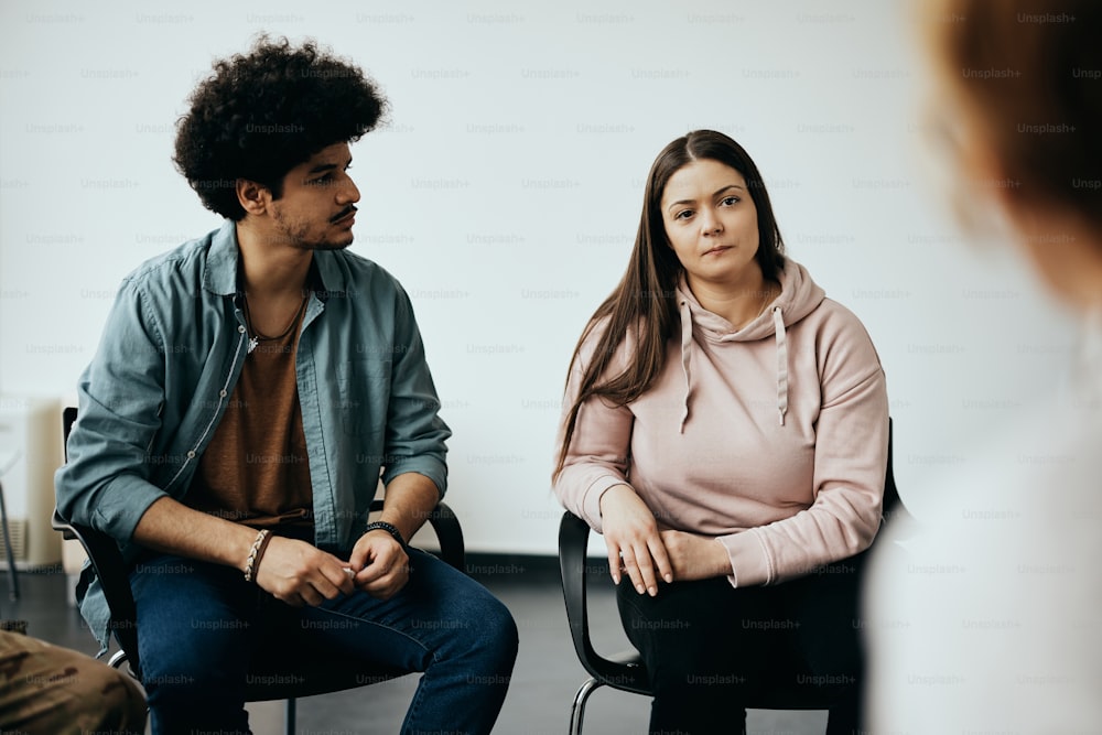 Muslim man and Caucasian woman having group therapy meeting with therapist at mental health center.