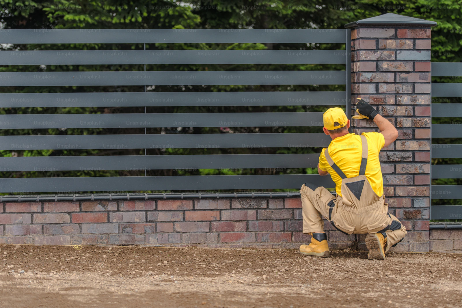 Fencing contractor building a metal panel fence on a residential property