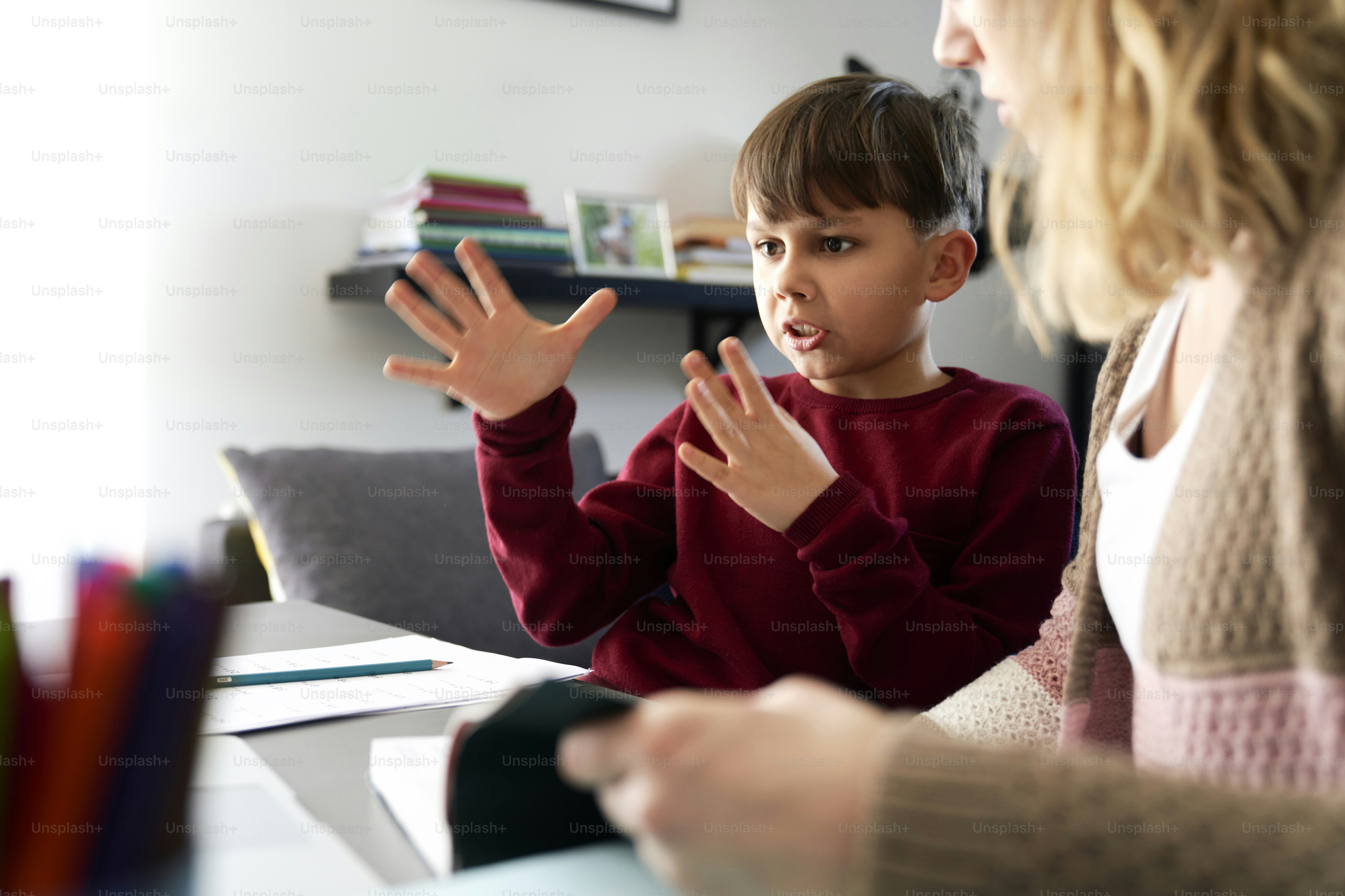 Boy gesturing during doing homework with his mother