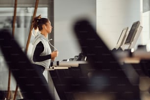 Athletische Frau, die auf der Laufstrecke joggt, während sie in einem Fitnessstudio trainiert.