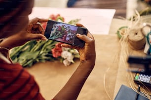 Close up of florist photographing flowers with cell phone at flower shop.