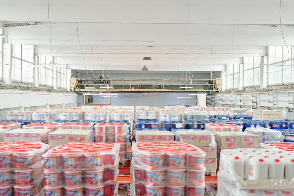 Interior do grande armazém contemporâneo do hipermercado de material de construção moderno com muitas pilhas de baldes e caixas de plástico