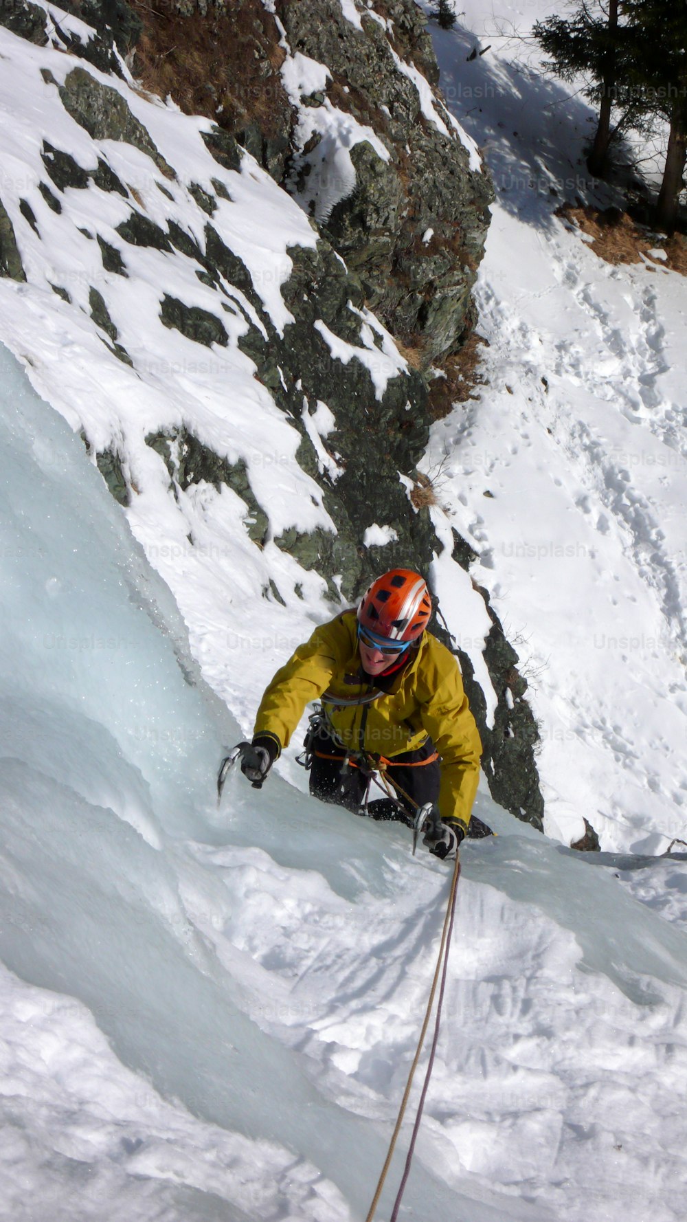 male mountain guide climbing a steep frozen waterfall on a cold winter day in the Alps of Switzerland