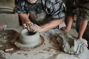 陶芸家が助手と工房でろくろに粘土を成形する接写