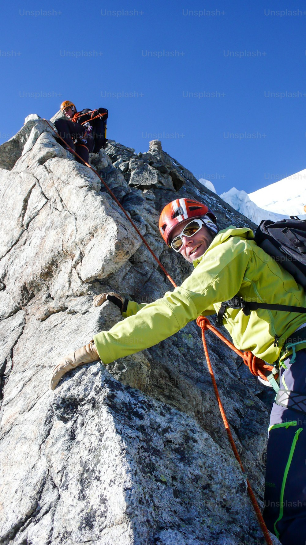 Bergführer führt männlichen Kunden an einem schönen Sommertag bei St. Moritz in der Berninagruppe auf den Gipfel eines hochalpinen Gipfels