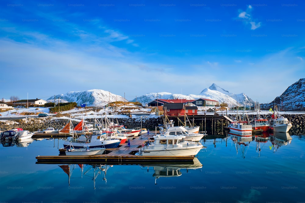 ノルウェーの冬のロフォーテン諸島の村にあるノルウェーのフィヨルドの桟橋での漁船とヨット