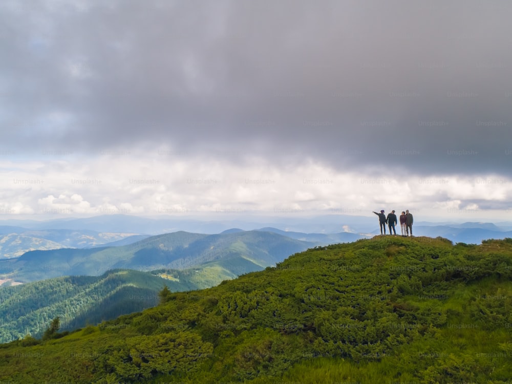Les quatre personnes debout sur une belle montagne contre le paysage nuageux