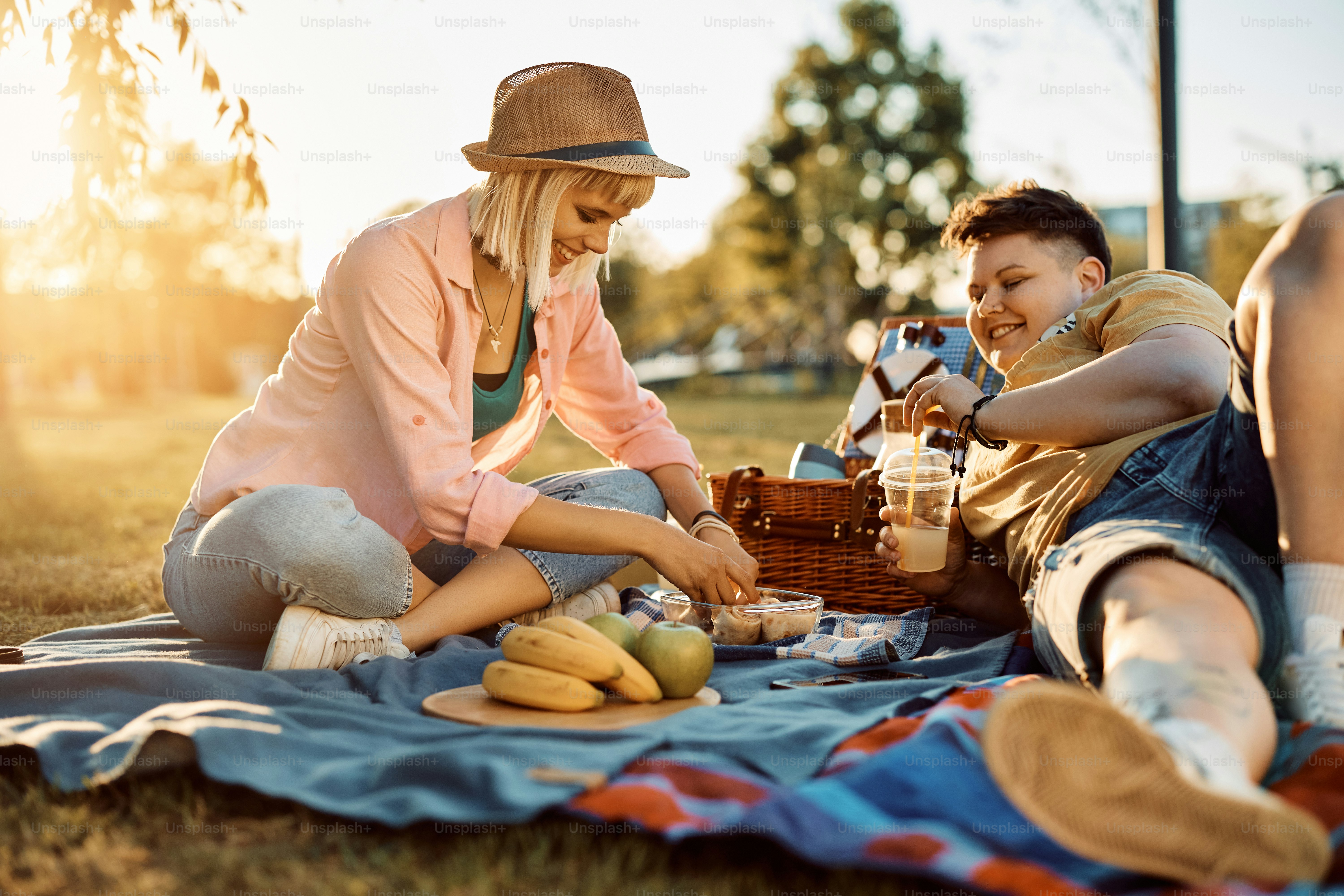 若い幸せなレズビアンと彼女のガール フレンドが公園で日没時にピクニックをしながら楽しんでいます の写真 Unsplashで見つける食物の無料写真