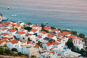 Sunset aerial view of seashore resort town on mediterranean coast. Romantic harbour and villas with red roofs waiting for vacationers