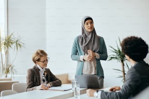 Giovane CEO musulmano che parla con il suo team aziendale durante una riunione in ufficio.